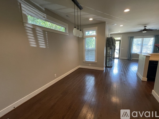 A spacious room with wooden flooring and a ceiling fan.