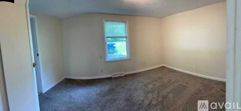A room with a window and carpeted floor.
