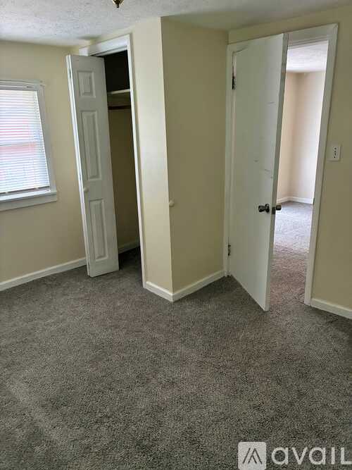 A room with a carpeted floor and two doors, one of which is open.
