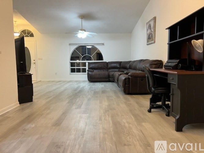 A living room with a black leather couch and a television on a stand.