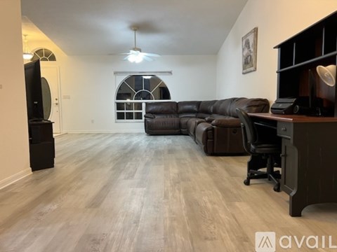 A living room with a black leather couch and a television on a stand.