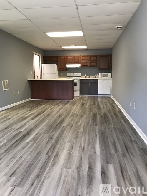 A kitchen with wood flooring and white appliances.