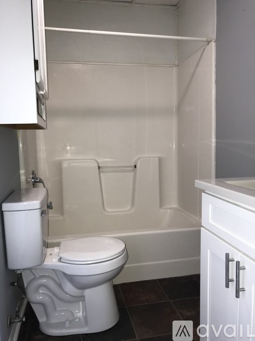 A white toilet with a white bath tub in a small bathroom.