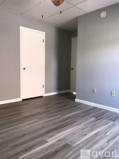 A room with a white door and grey walls.