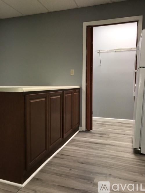 A kitchen with a white fridge and wooden floors.