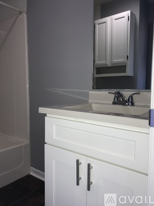 A white bathroom vanity with a mirror and a white bathtub.