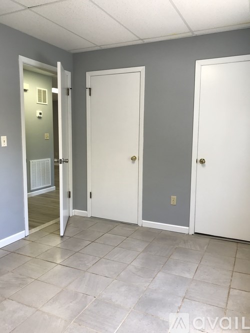 Three white doors in a room with tile flooring.