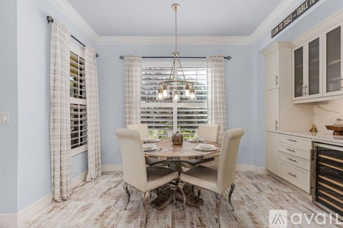 A dining room with a table set for four and a chandelier hanging from the ceiling.