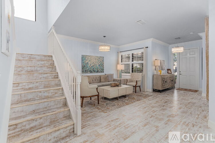 A spacious living room with a staircase and a painting on the wall.