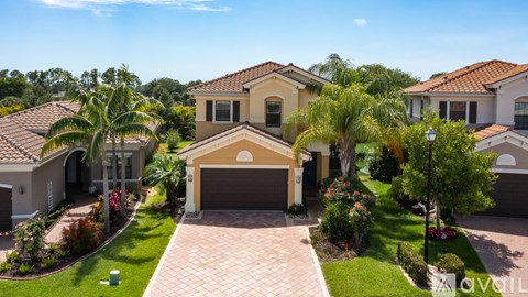 A house with a driveway and a garage is surrounded by greenery.
