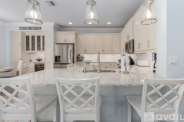 A kitchen with white chairs and a marble countertop.
