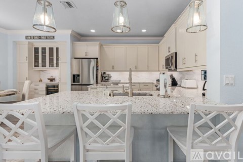 A kitchen with white chairs and a marble countertop.