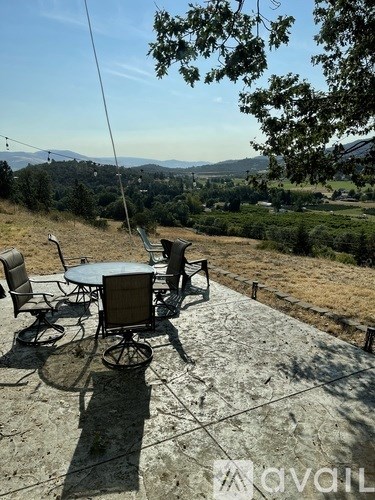 A table and chairs are set up on a stone patio with a view of the countryside.