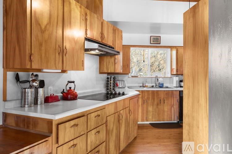 A car is parked on a driveway with a house and trees in the background.