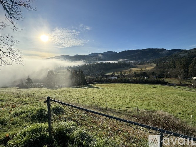 A fence in the foreground with a field and mountains in the background.