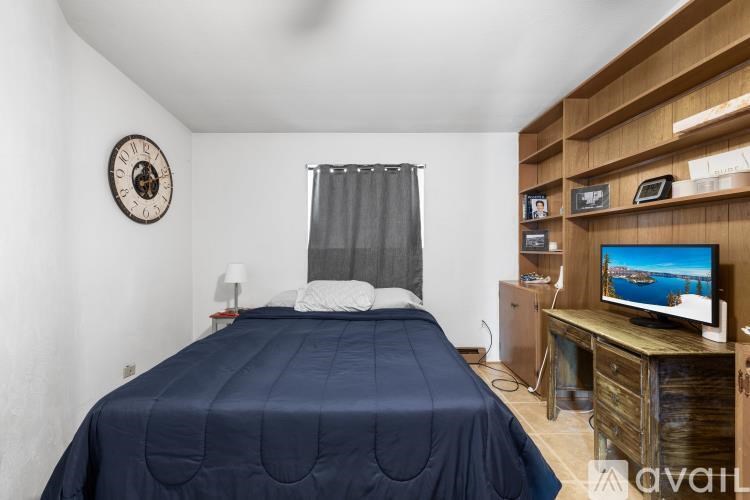 A bedroom with a bed, a television, and a clock on the wall.