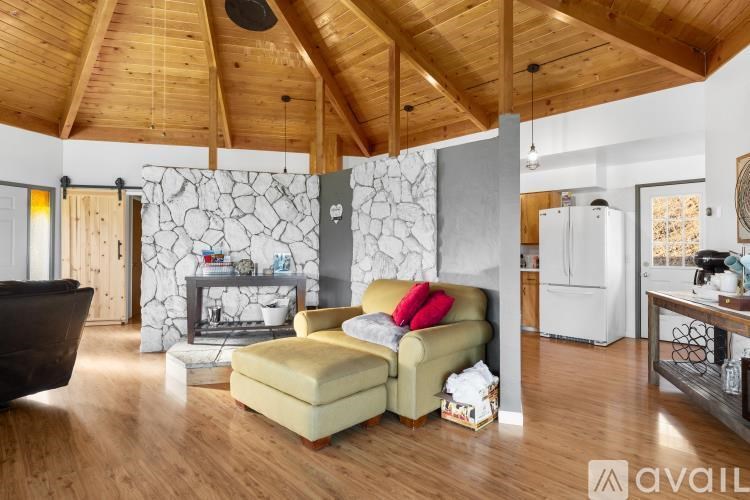 A living room with a yellow couch and a stone wall.