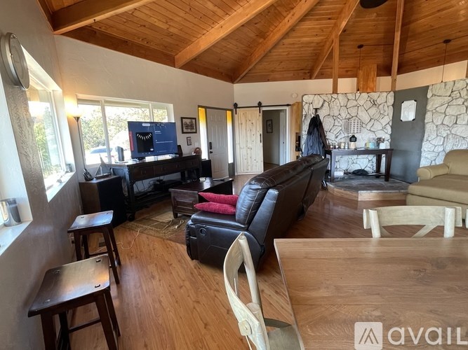 A living room with a black couch and wooden floors.