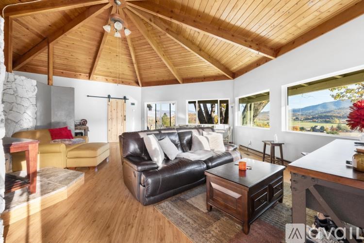 A living room with a black leather couch and wooden floors.