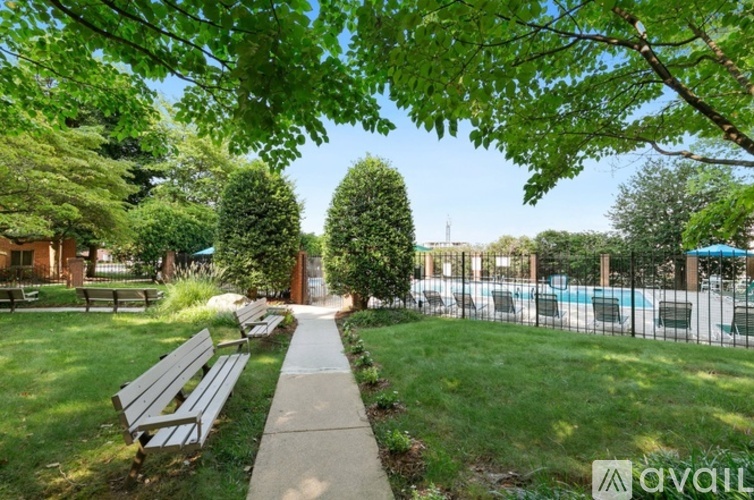 A park with a walking path, benches, and a pool.