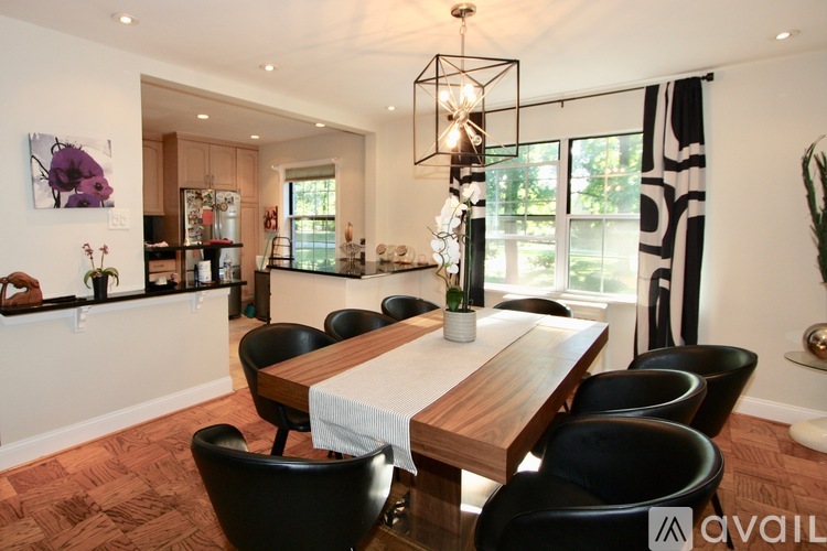 A modern dining room with a wooden table and black chairs.