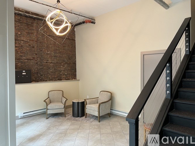 A room with a staircase, two chairs, and a table.