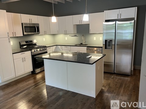 A kitchen with white cabinets and a black countertop.