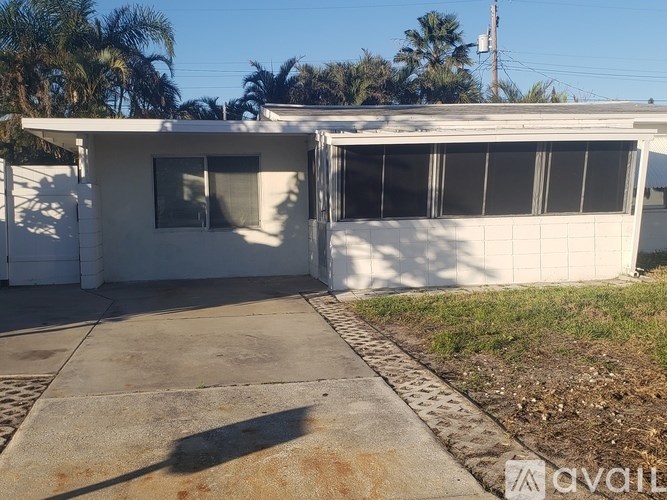 A white building with a garage door open and a driveway leading to it.