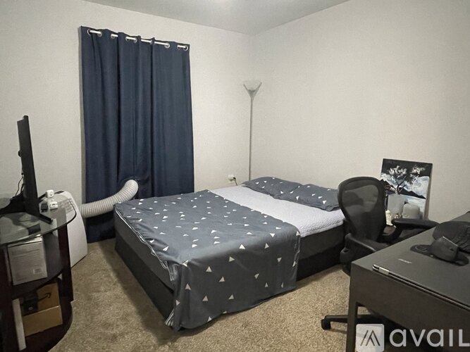 A bedroom with a bed, desk, chair, and a television.
