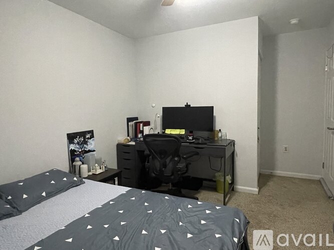 A bedroom with a bed, desk, chair, and two lamps.