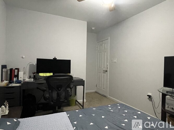 A bedroom with a bed, desk, chair, and two lamps.