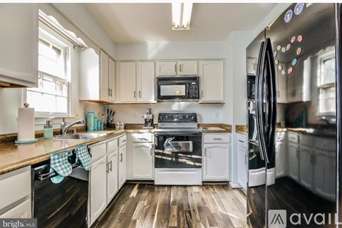 A kitchen with white cabinets and a wooden floor.