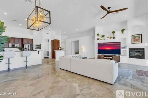 A modern living room with a white sofa and a large TV on the wall.