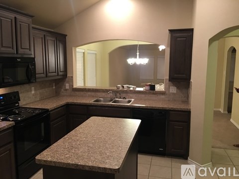 A kitchen with dark brown cabinets and a granite countertop.