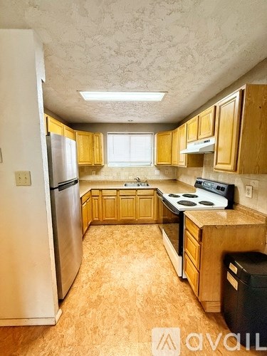 A kitchen with wooden cabinets and a stainless steel refrigerator.