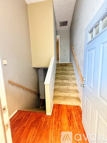 A hallway with a staircase leading to a door.
