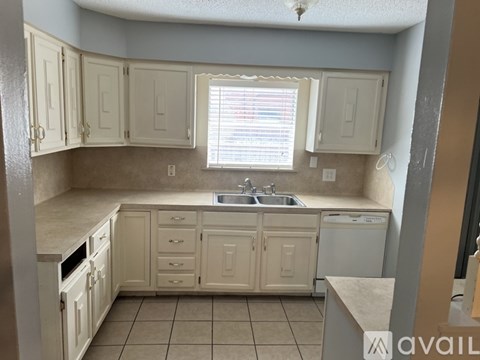 A kitchen with white cabinets and a beige countertop.