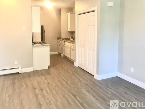 A kitchen with white cabinets and a wooden floor.