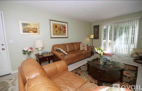 A living room with a brown leather couch and a glass coffee table.