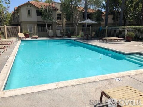 A pool surrounded by a fence and a patio area.