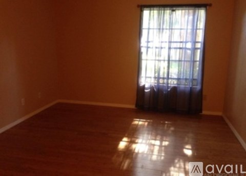 A room with wooden flooring and a window with curtains.