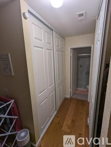 A hallway with a white door and a white wall.