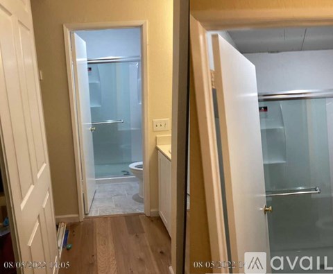 A bathroom with a glass shower door and a wooden floor.