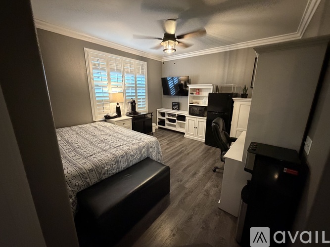 A white door opens to a room with a ceiling fan and a person standing.