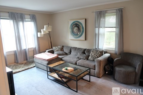 A living room with a grey couch, a coffee table, and a painting on the wall.
