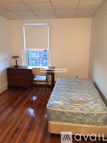 A bedroom with a bed, chair, and window.