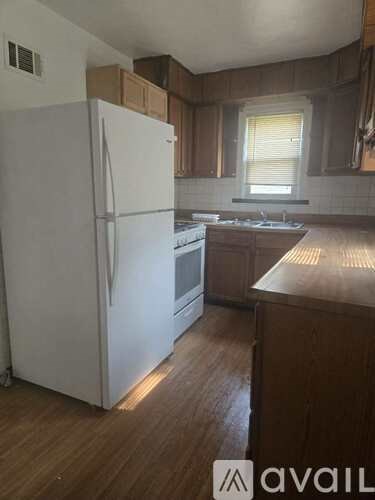 A kitchen with a white refrigerator and wooden cabinets.