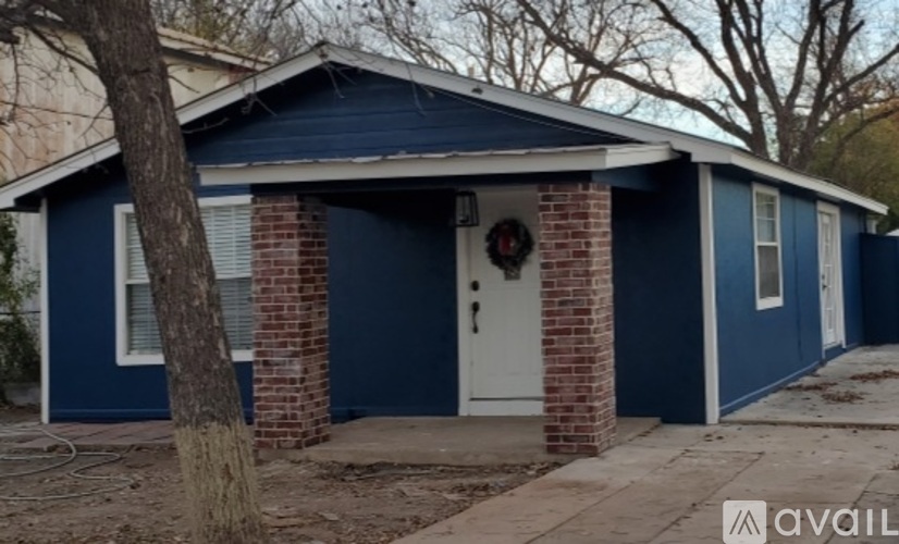 A small blue house with a white door and a wreath on the door.