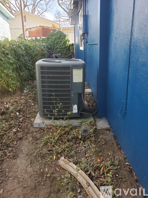 An old air conditioning unit sits outside next to a blue wall.