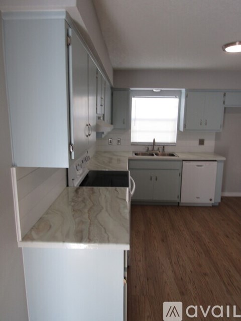 A kitchen with white cabinets and a wooden floor.